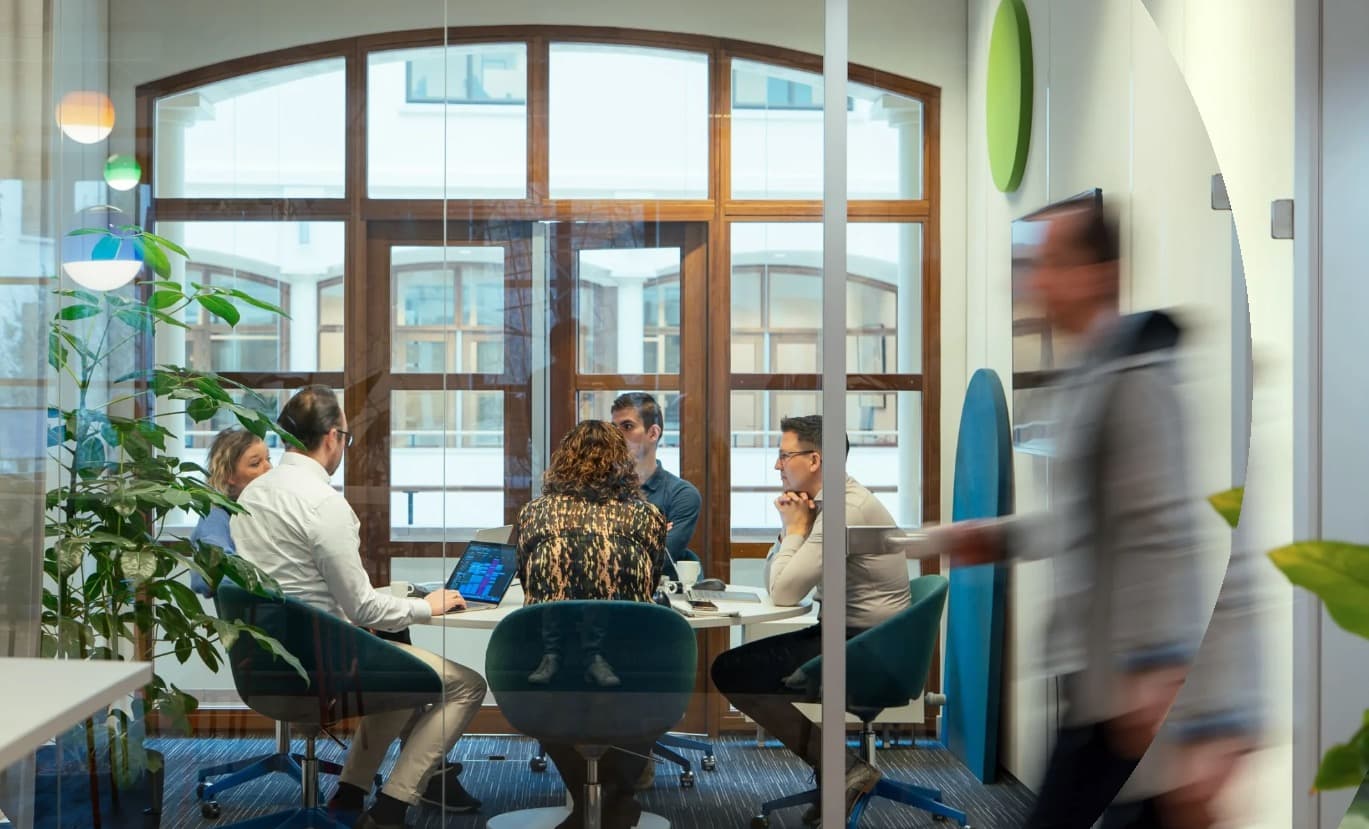 A team meeting in a room with tall arched windows